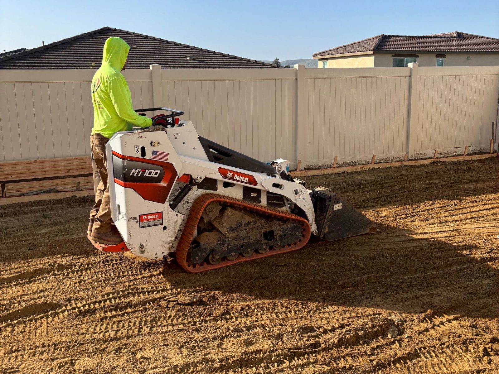 Mini track loader fine grading a backyard