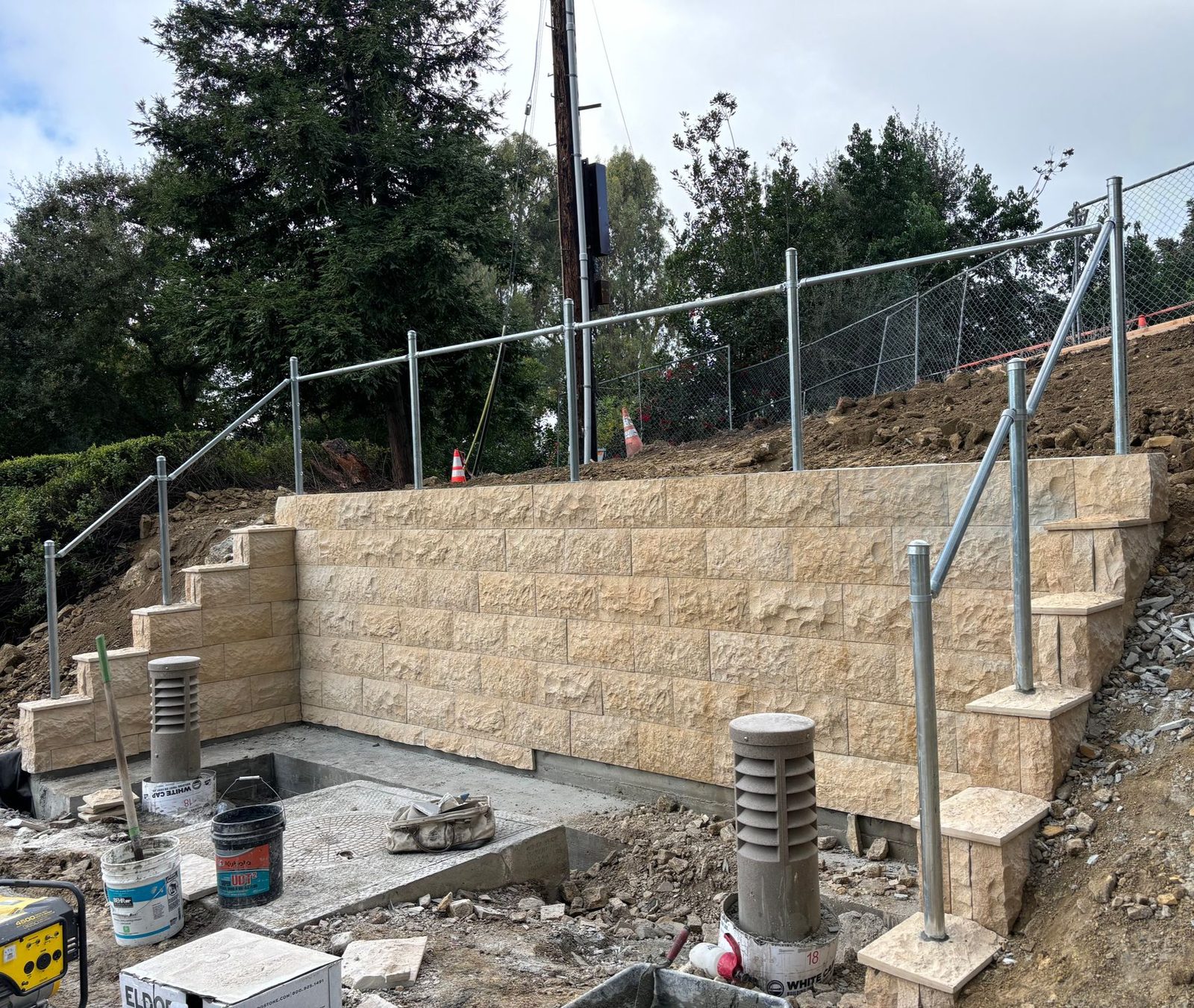 Split-face block retaining wall under construction with stepped footing