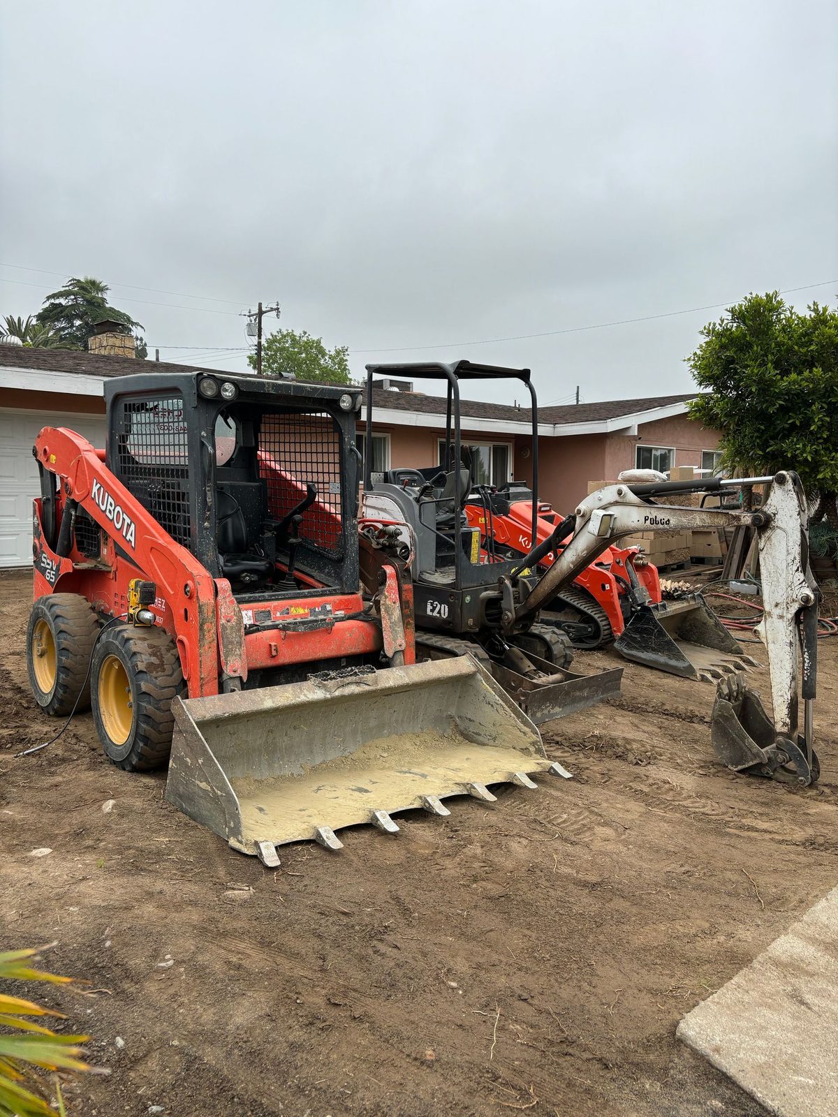 Track loader and mini excavator working a backyard
