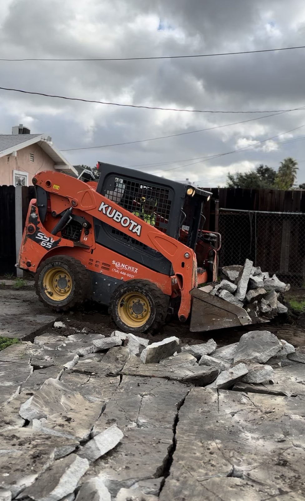 Kubota track loader loading broken concrete in a residential backyard