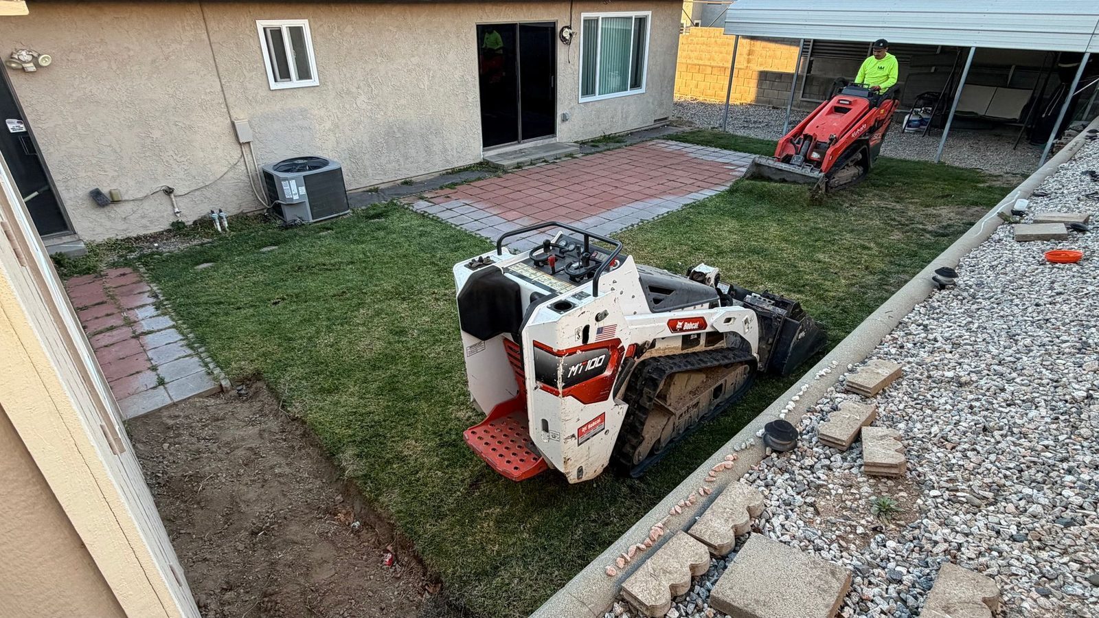 Mini track loader working a residential backyard