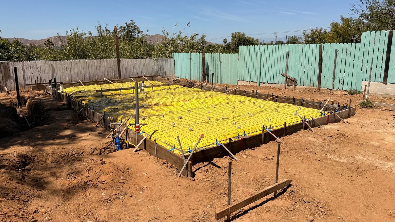 Formed ADU foundation with yellow vapor barrier and rebar grid ready for inspection
