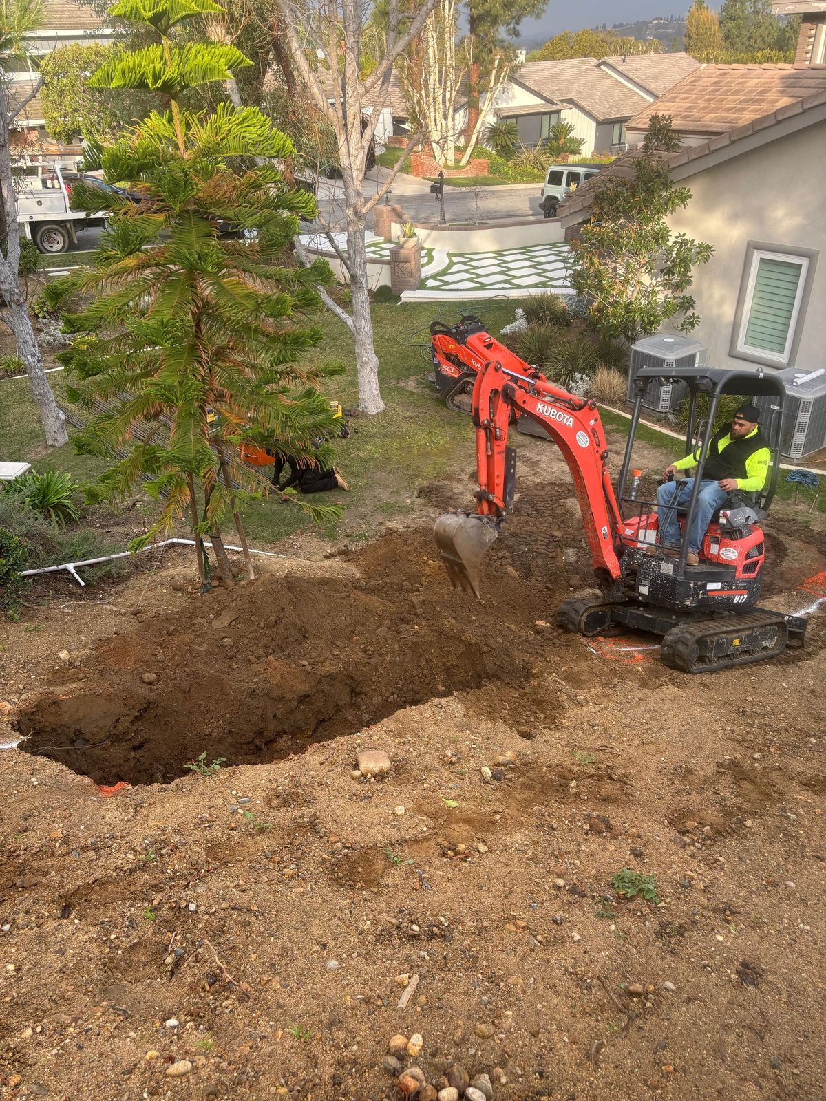 Mini excavator digging along a property line