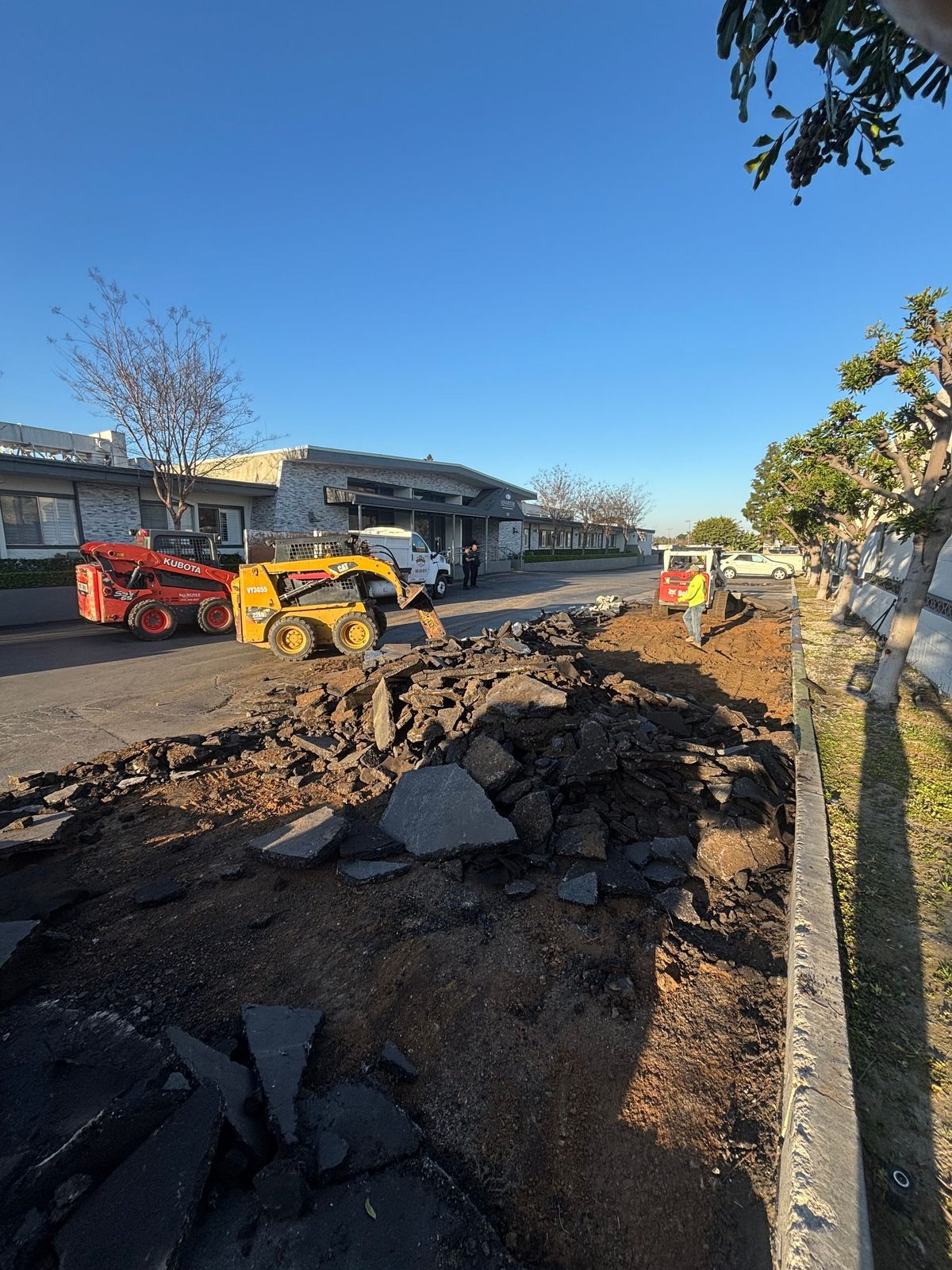 Skid steer loading broken asphalt and concrete at a commercial site